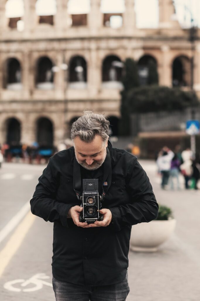 Marcin Ławrysz z aparatem dwuobiektywowym przed Koloseum w Rzymie